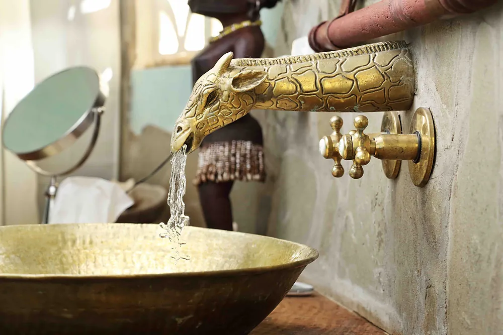 Water pouring from a brass serpent tap into a hammered brass basin