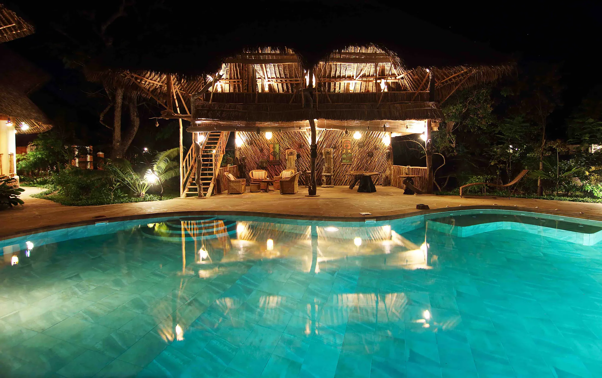 Both houses lit at night with the pool between them