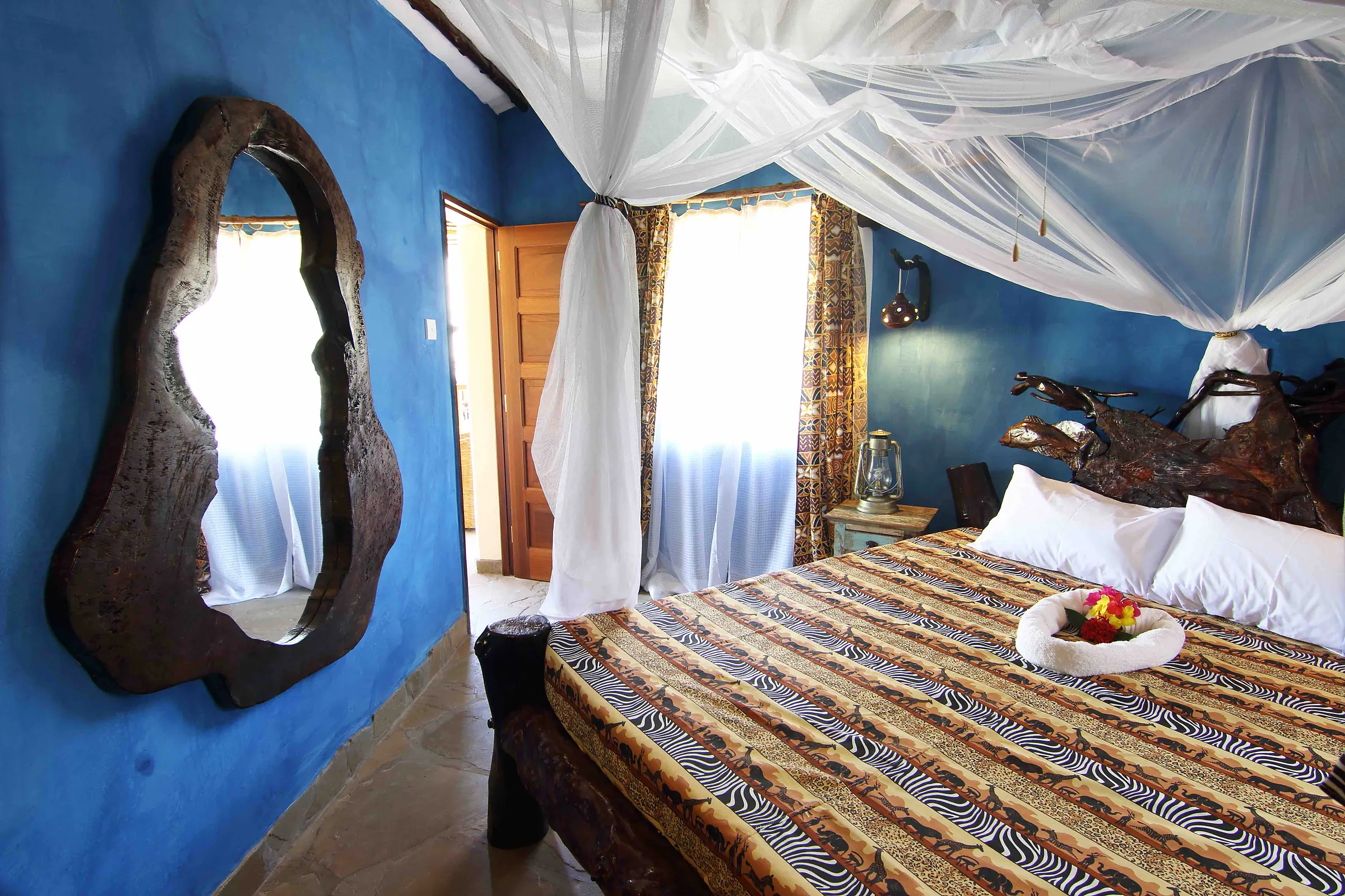 Blue bedroom with a four-poster bed and a carved mirror