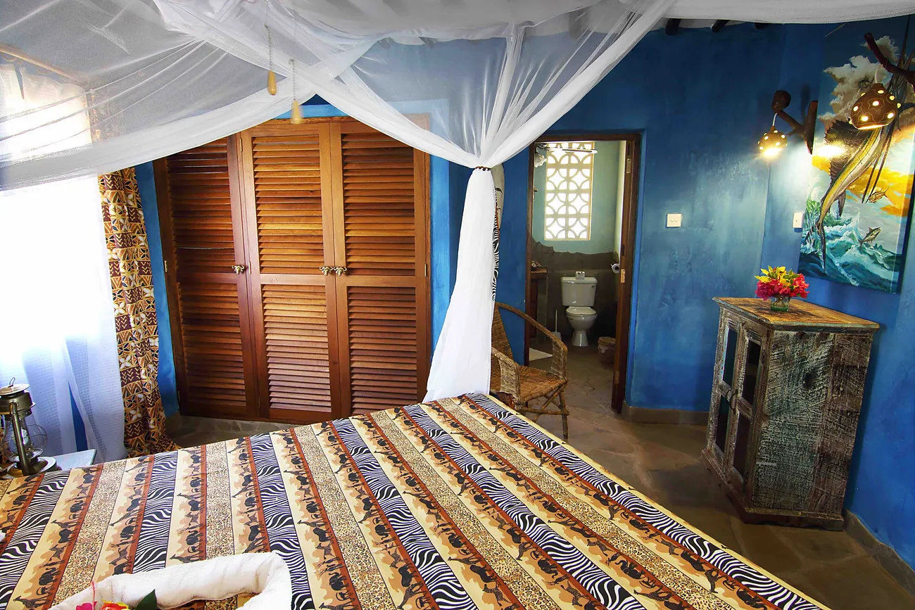 Blue-walled bedroom with a four-poster bed and wooden louvre doors